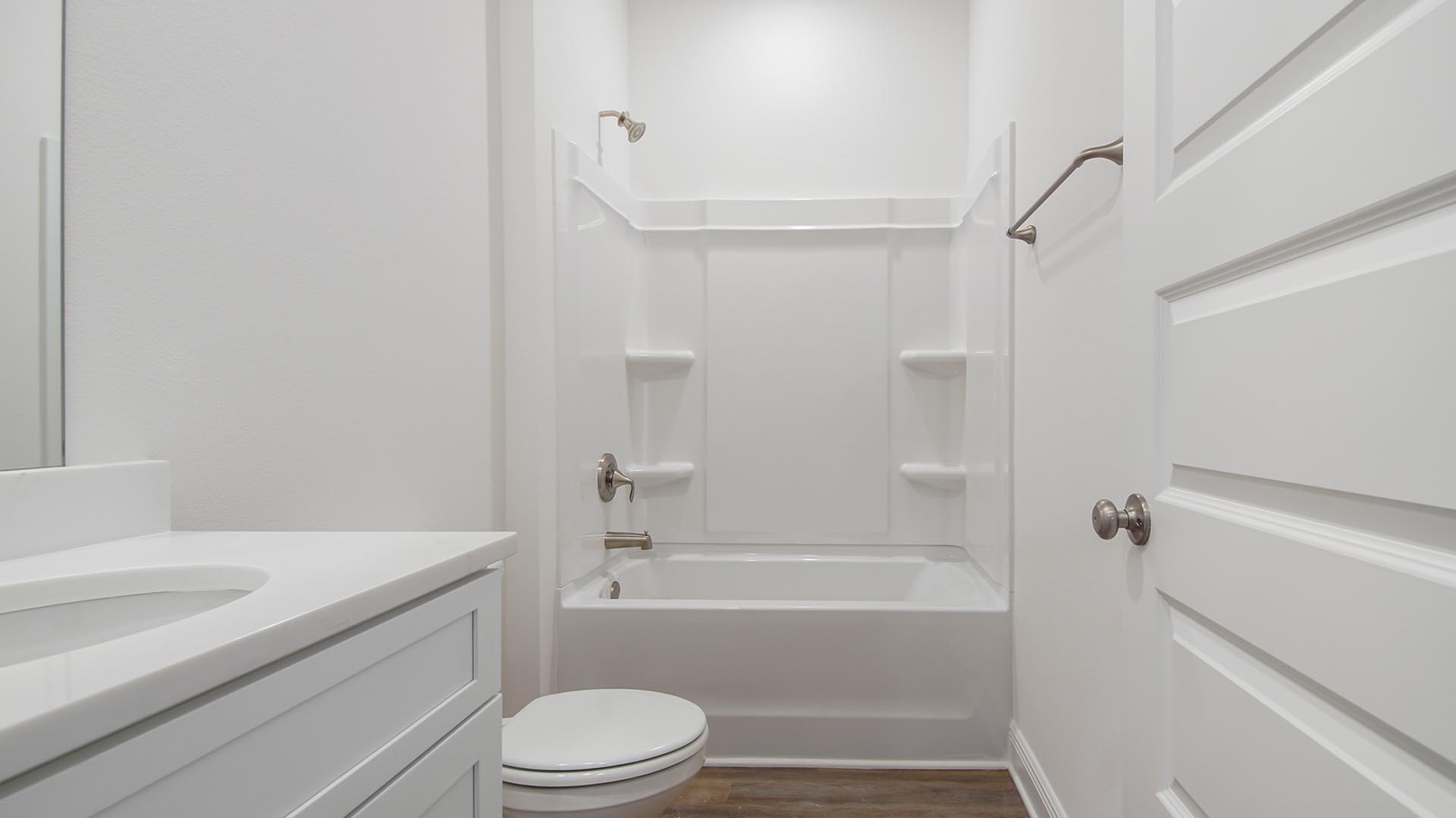 Shared bathroom located off the entry hall features a vanity and shower tub combination