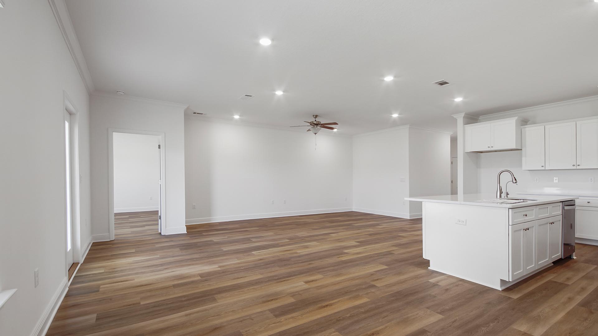 The open kitchen faces the living area that has a ceiling fan