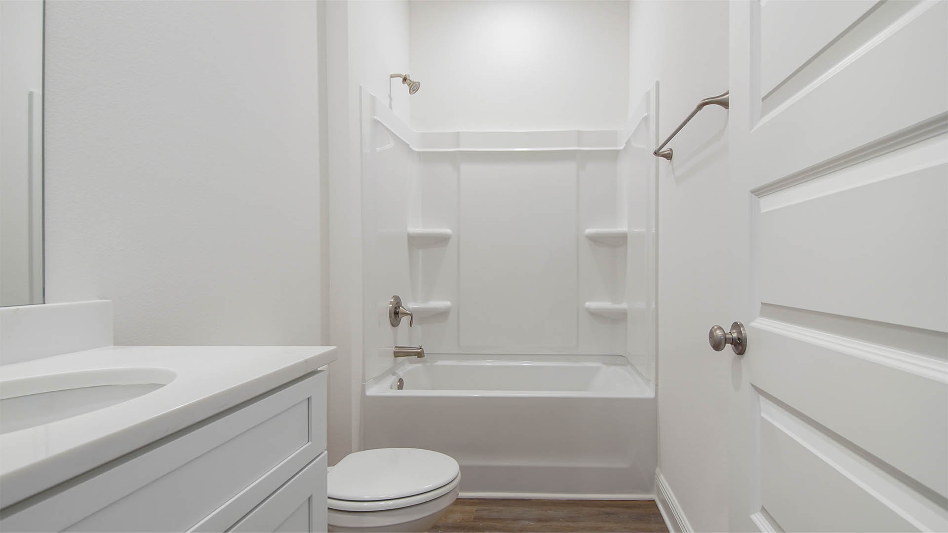 Bathroom with white cabinets and shower and quartz countertops.