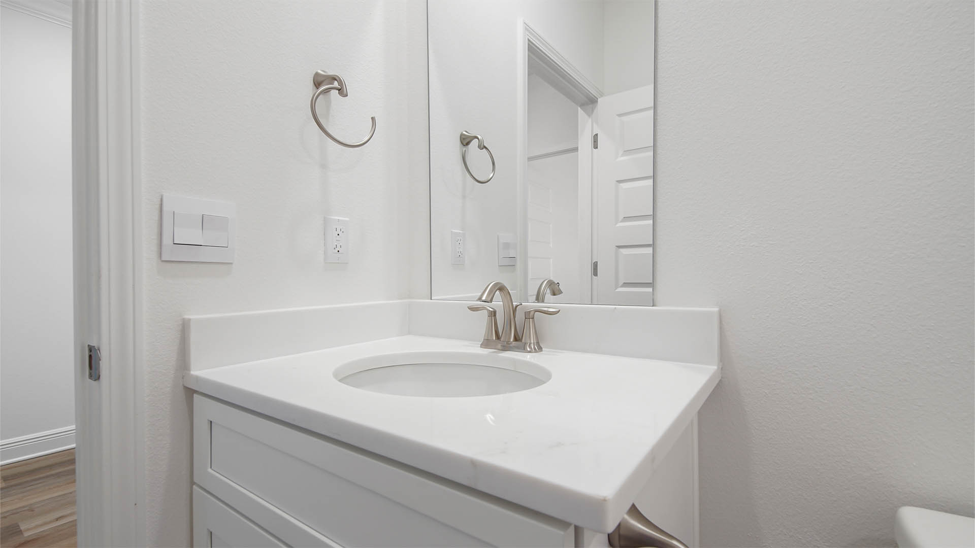 Bathroom with white cabinetry and single vanity with quartz countertops.