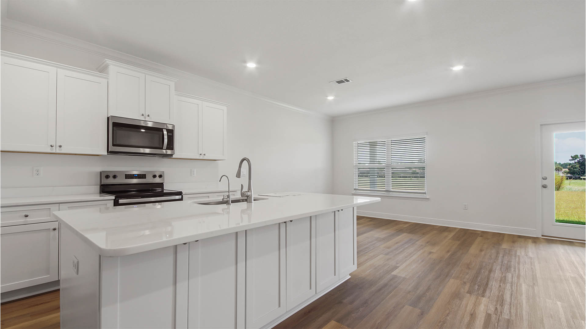 Open kitchen with island with white cabinets and quarts countertops and pantry and EVP flooring and dining area with windows..