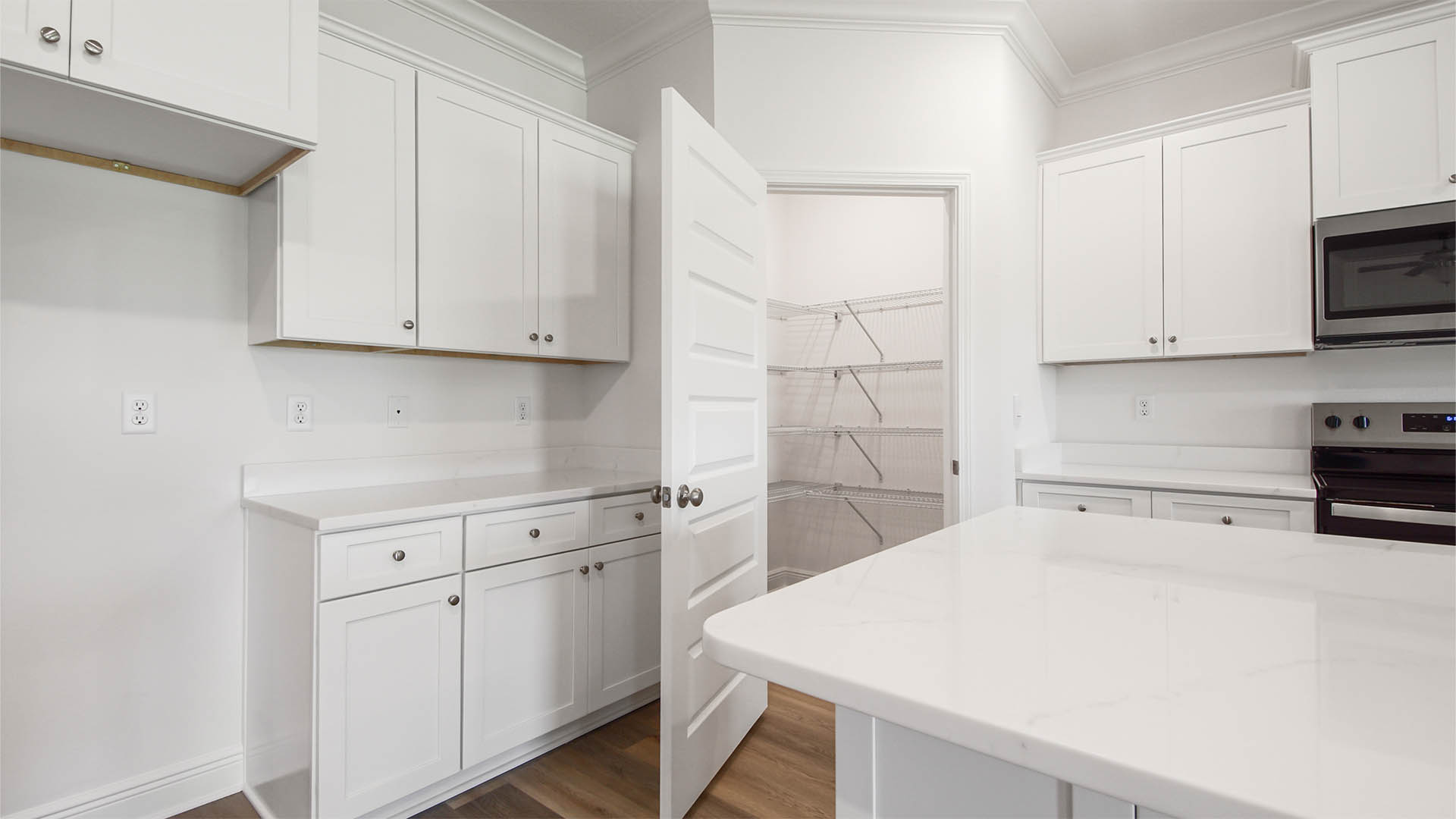 Open kitchen with island and quartz countertops and pantry.