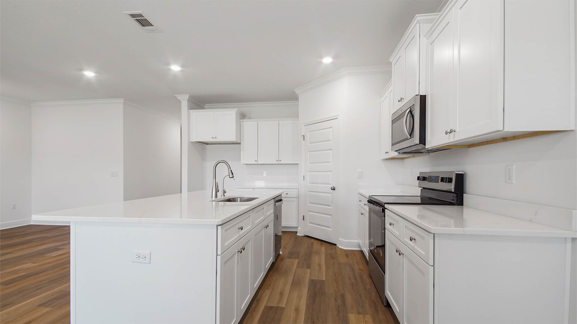 Open kitchen with island and quartz countertops and pantry.