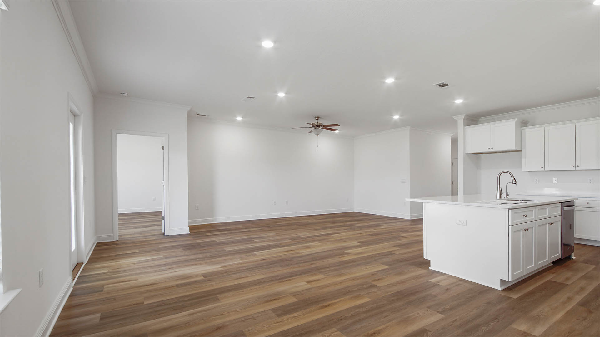 Open Living room with EVP flooring and ceiling fan and kitchen island with quartz countertops.