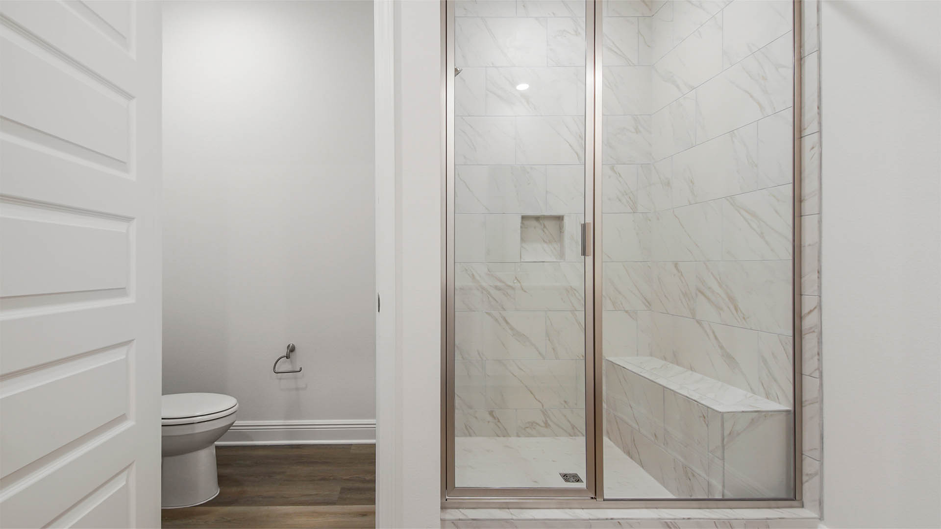 Primary bathroom with tile shower next to water closet.