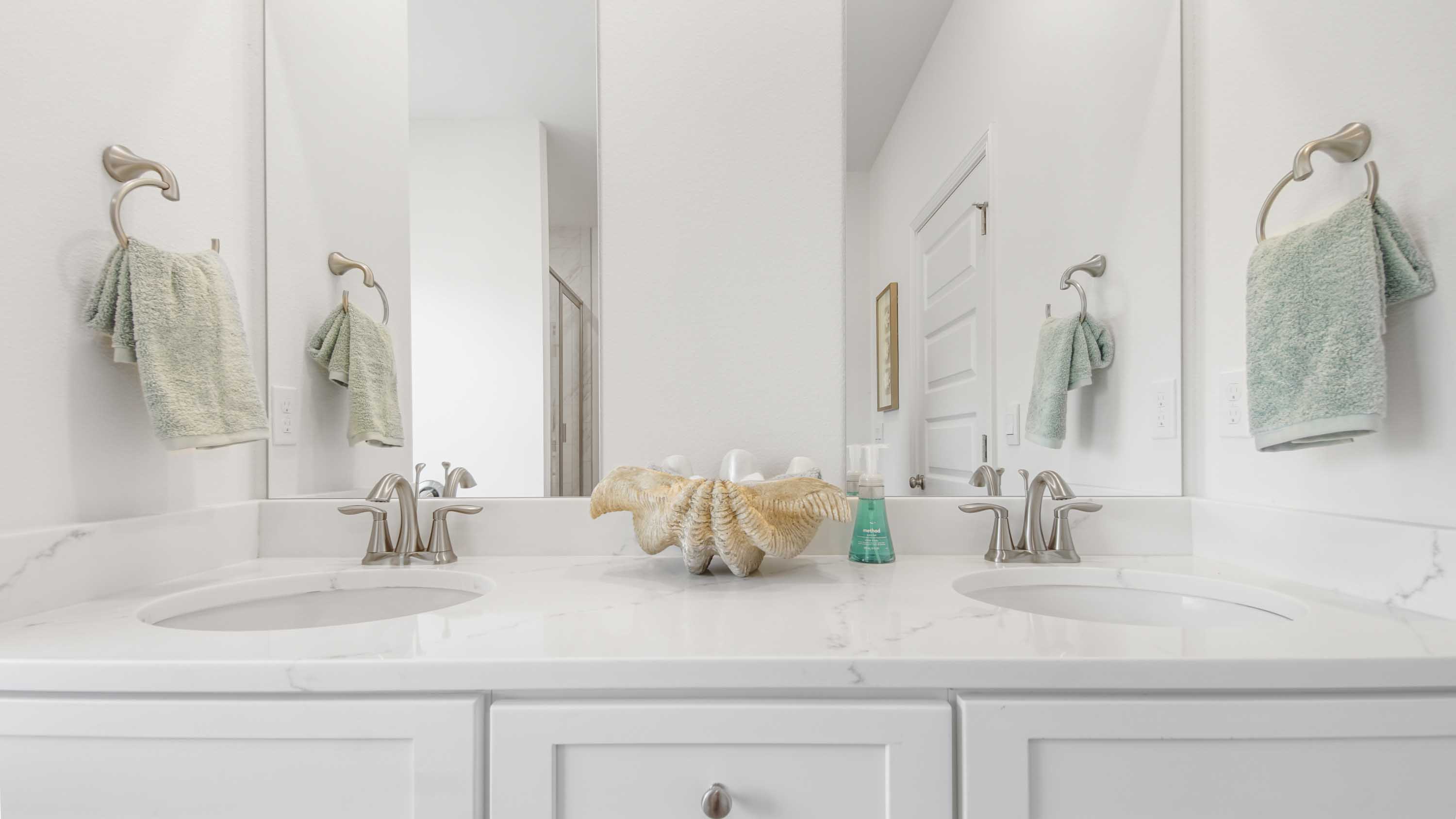 Primary bathroom double sink vanity with quartz countertops and two mirrors