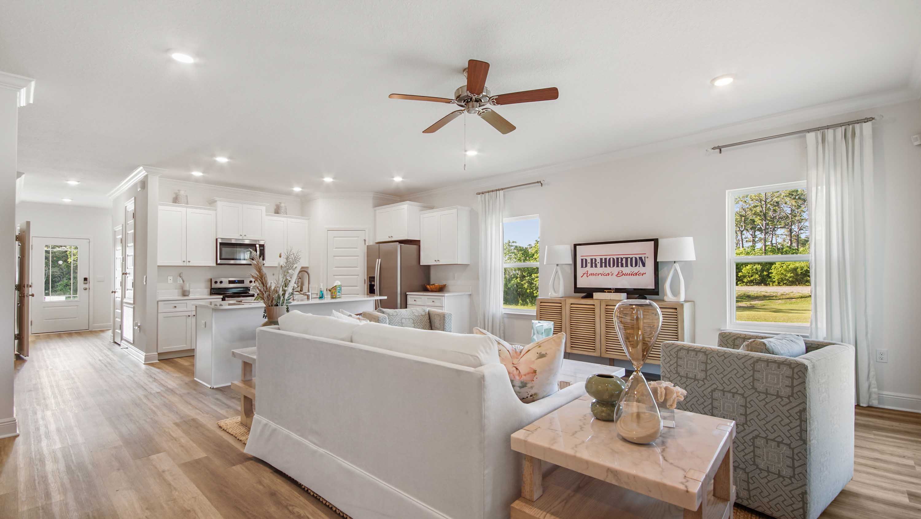 Open living area next to kitchen with EVP flooring and windows.
