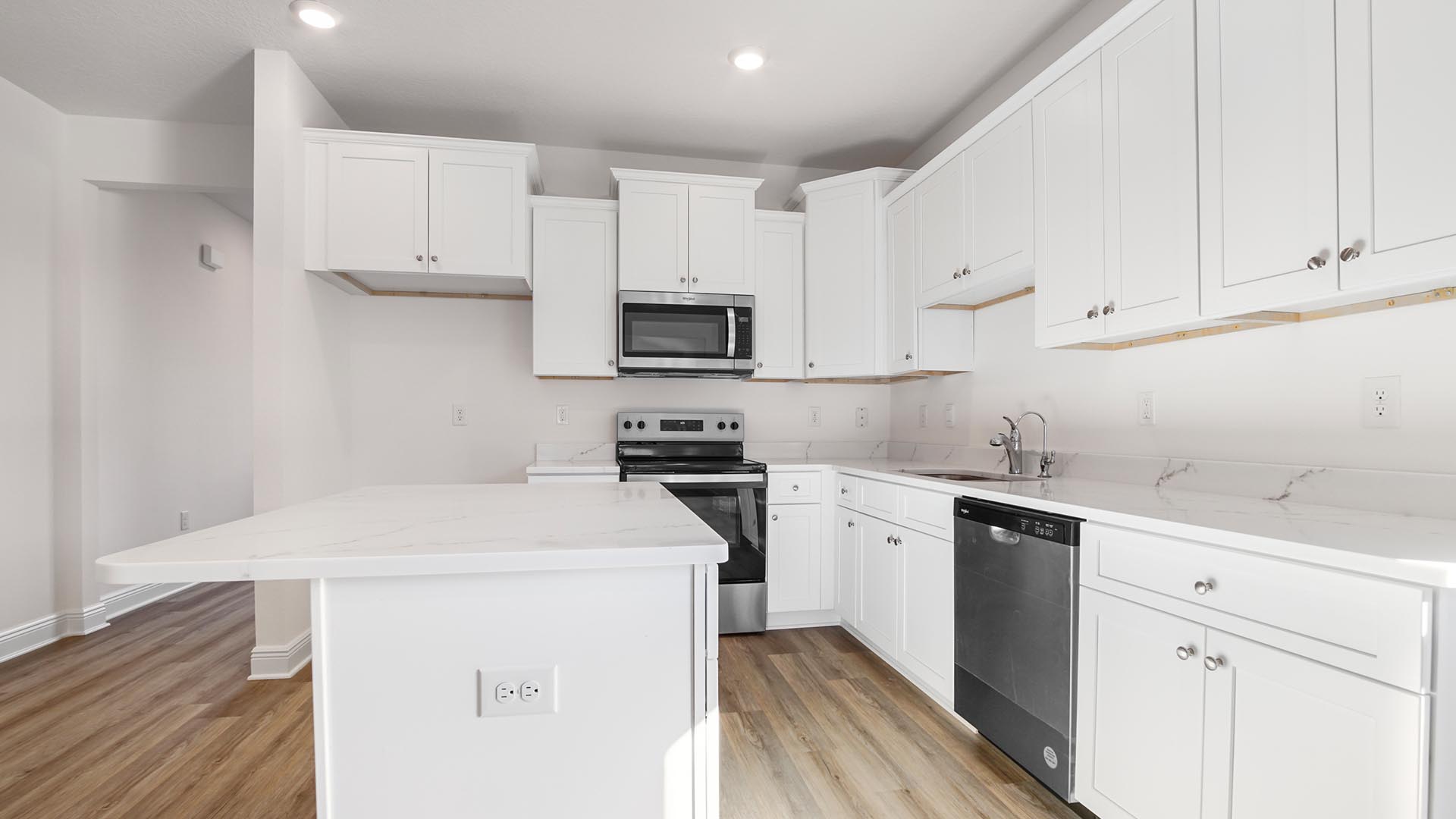 Kitchen with white cabinetry and quartz countertops and stainless steel appliances.
