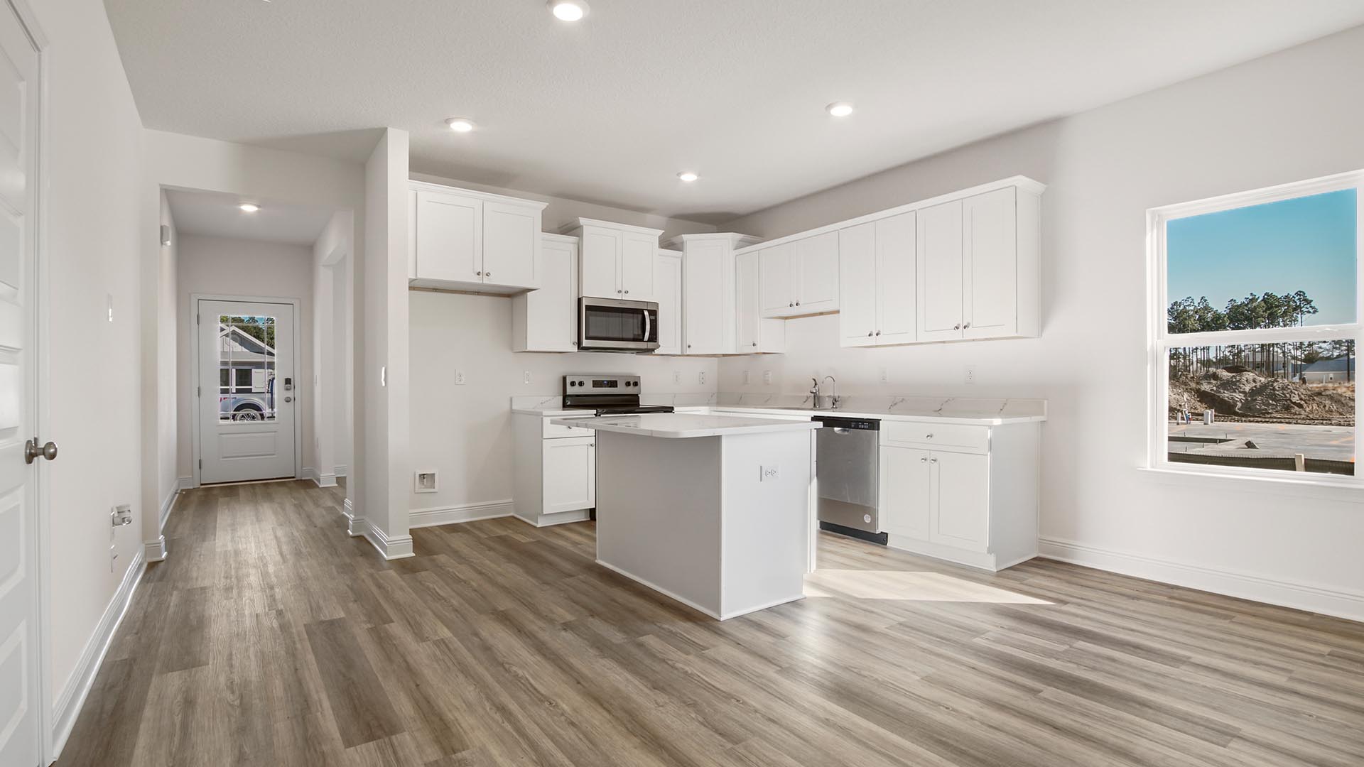 Bright open living area with kitchen and dining room flowing into living room with multiple windows and EVP flooring.