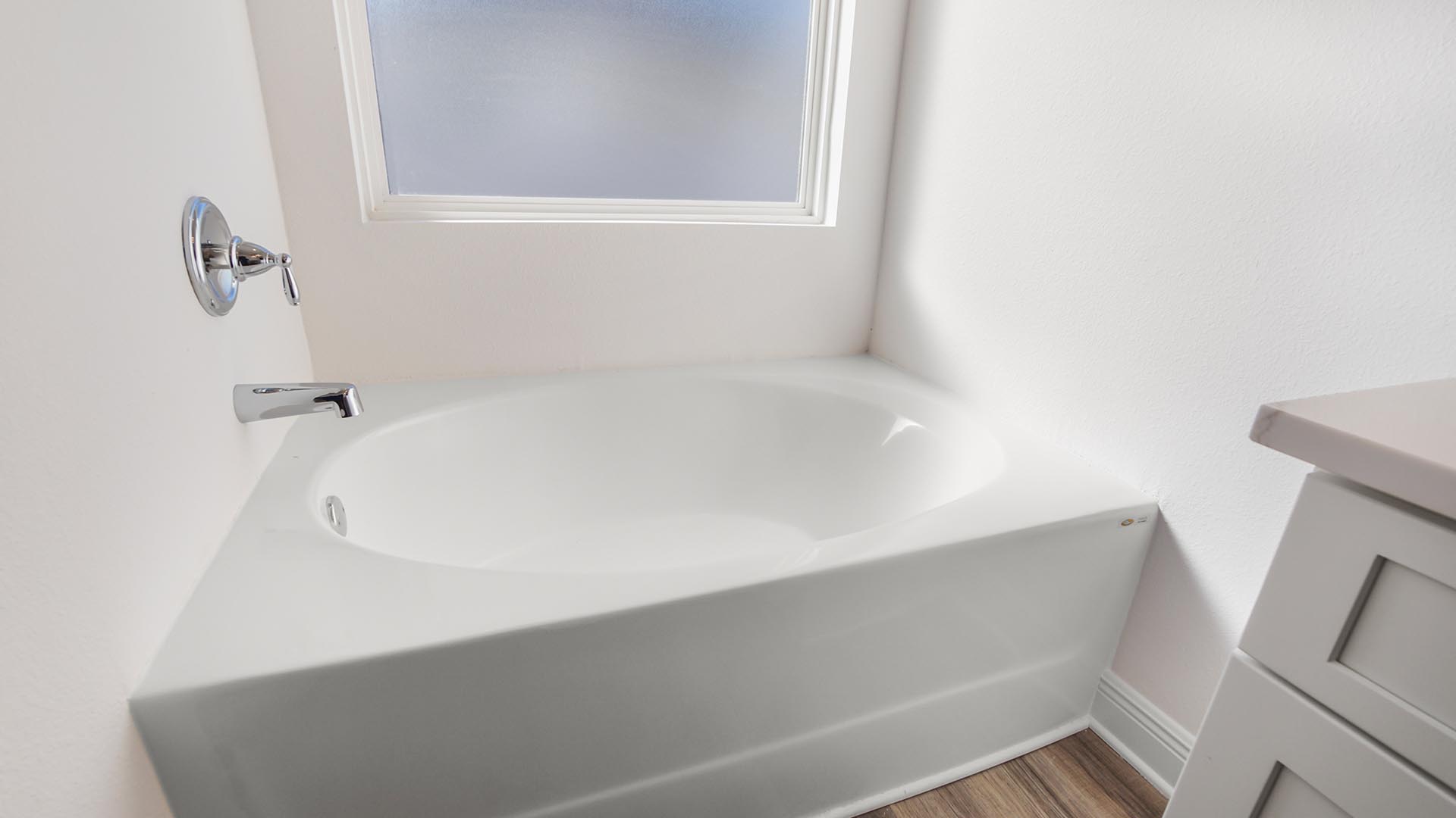 Primary bathroom with large soaking tub below a frosted glass window and a separate standing shower.