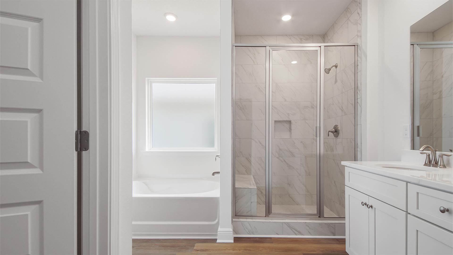 The primary bath has a large soak tub and separate shower with tile and glass enclosure