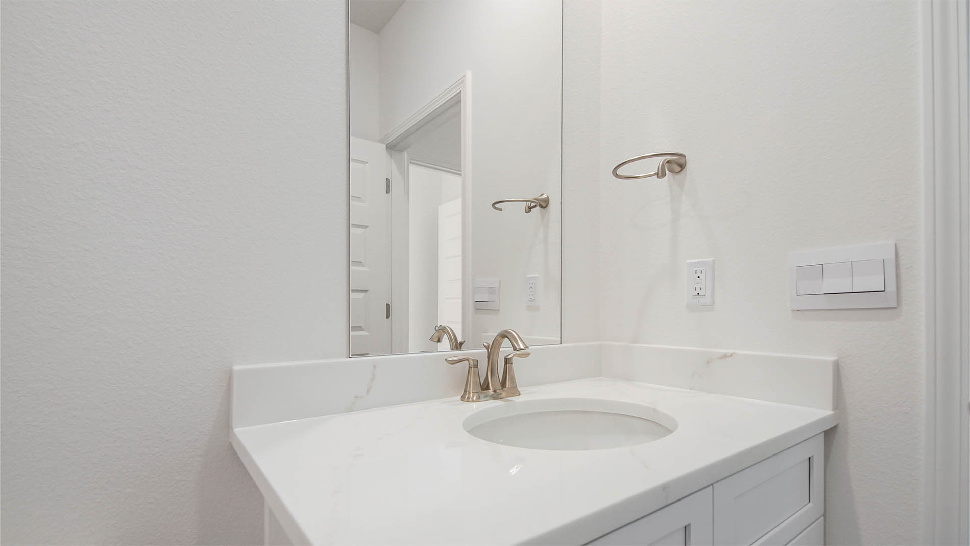 Bathroom with single vanity with quartz countertops and white cabinets.