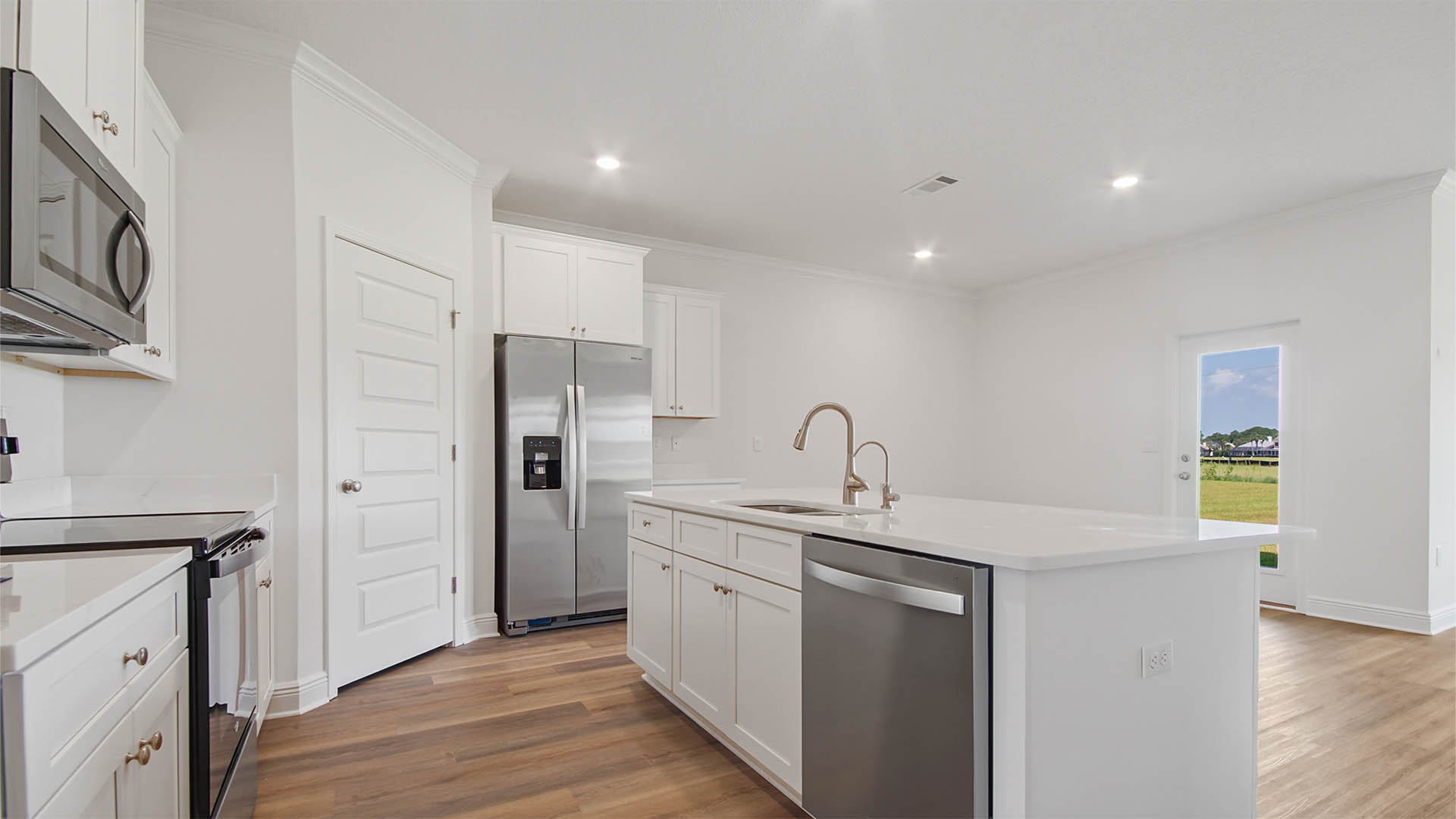 Kitchen with large island and EVP flooring and white cabinetry and quarts countertops.