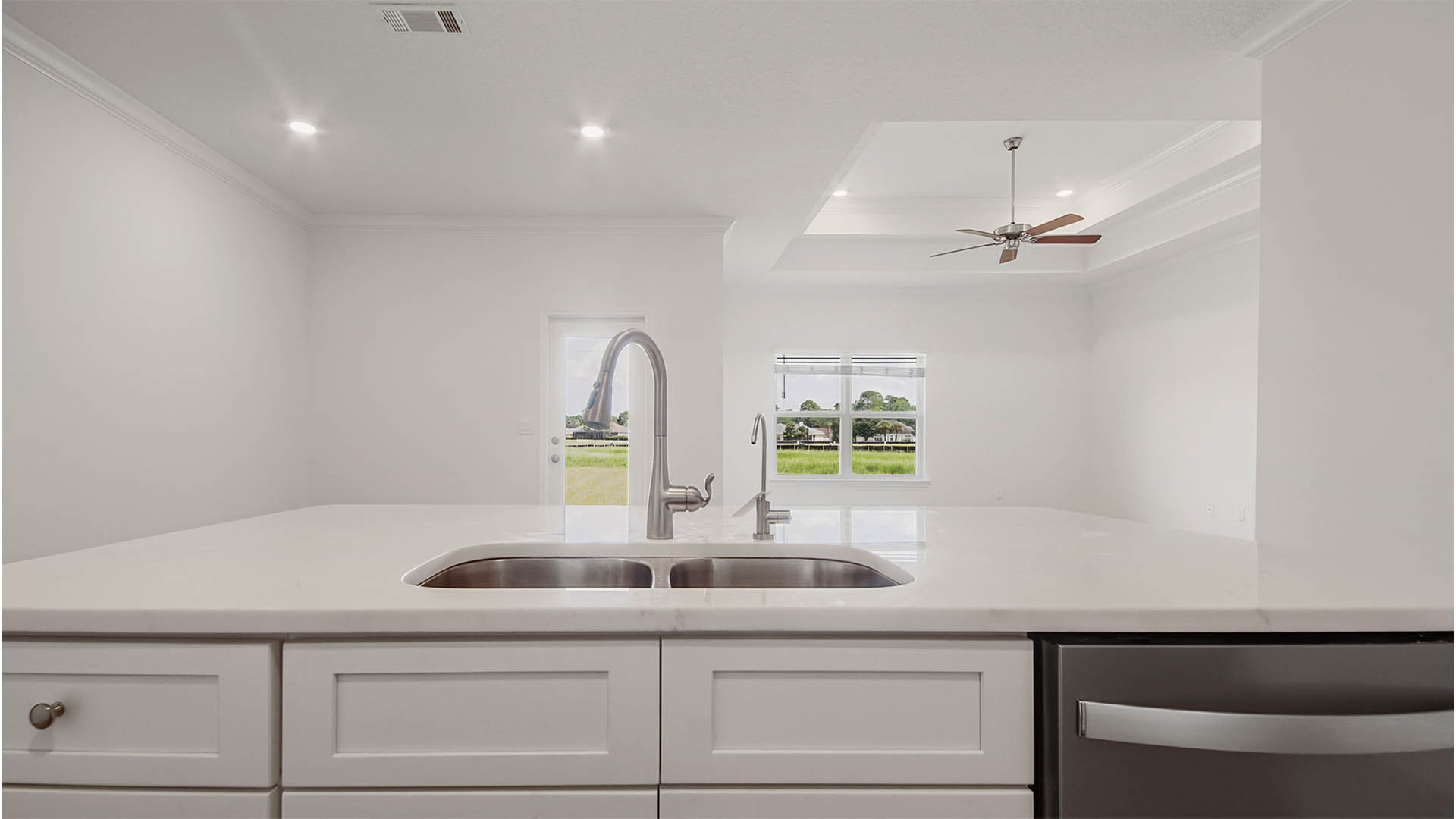 Large kitchen island with quartz countertops and white cabinetry and dishwasher.