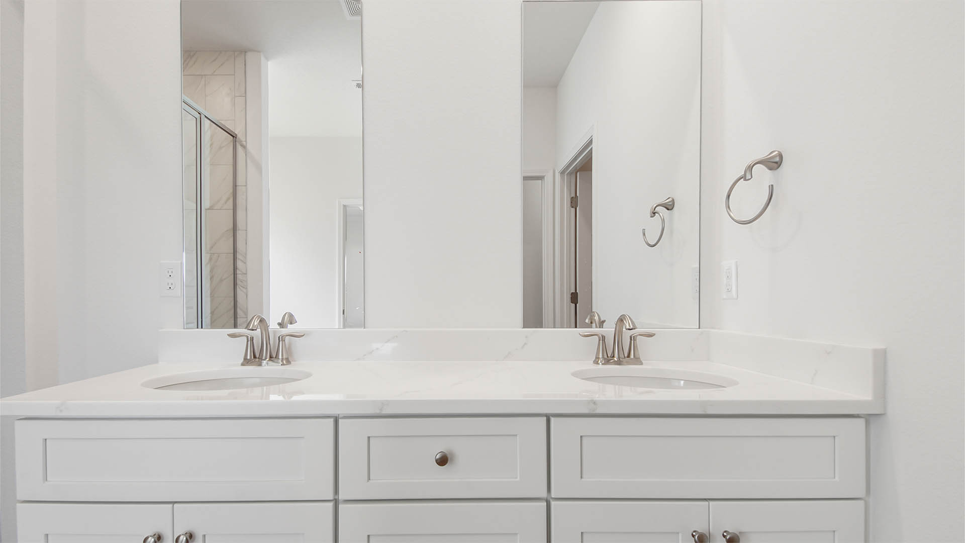 Primary bathroom with double vanity and quartz countertops and two mirrors.