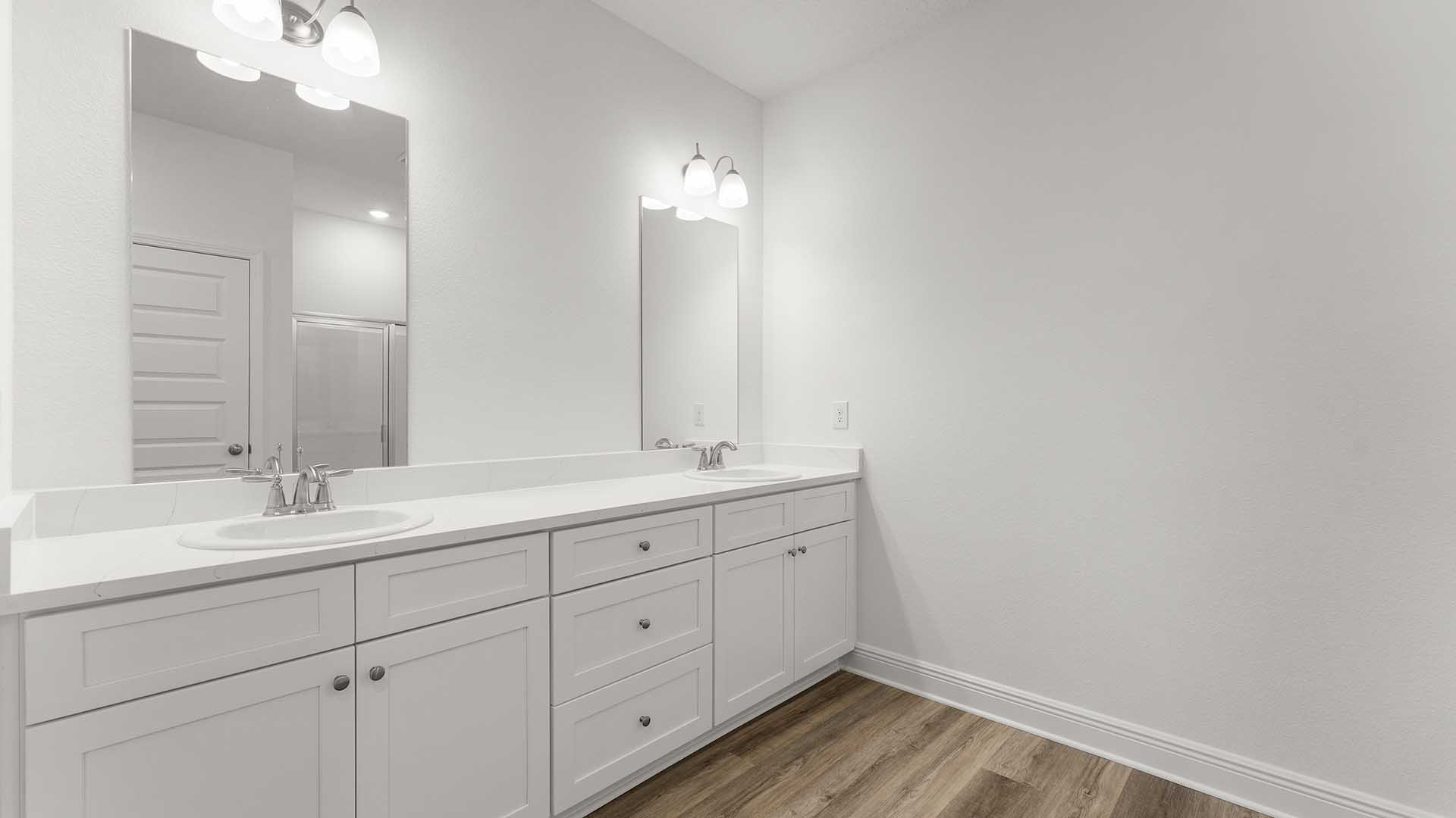 Primary bathroom with double vanity with white cabinetry and quartz countertops.