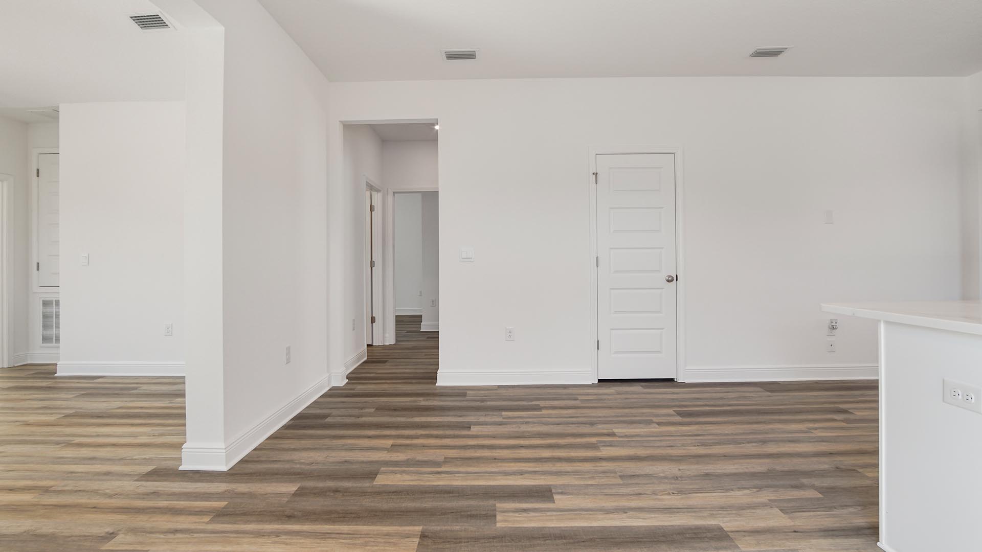 Bright open living area with kitchen and dining room flowing into living room with multiple windows and EVP flooring.