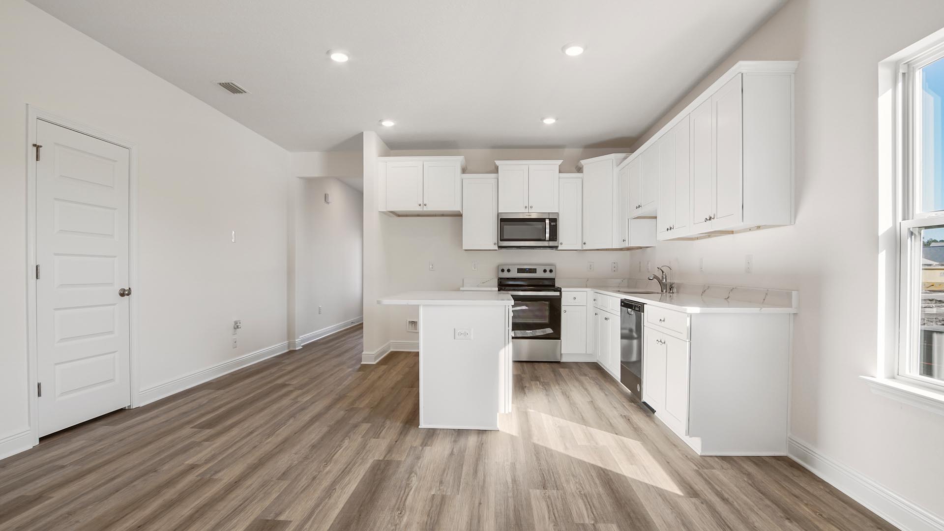 Bright open living area with kitchen and dining room flowing into living room with multiple windows and EVP flooring.