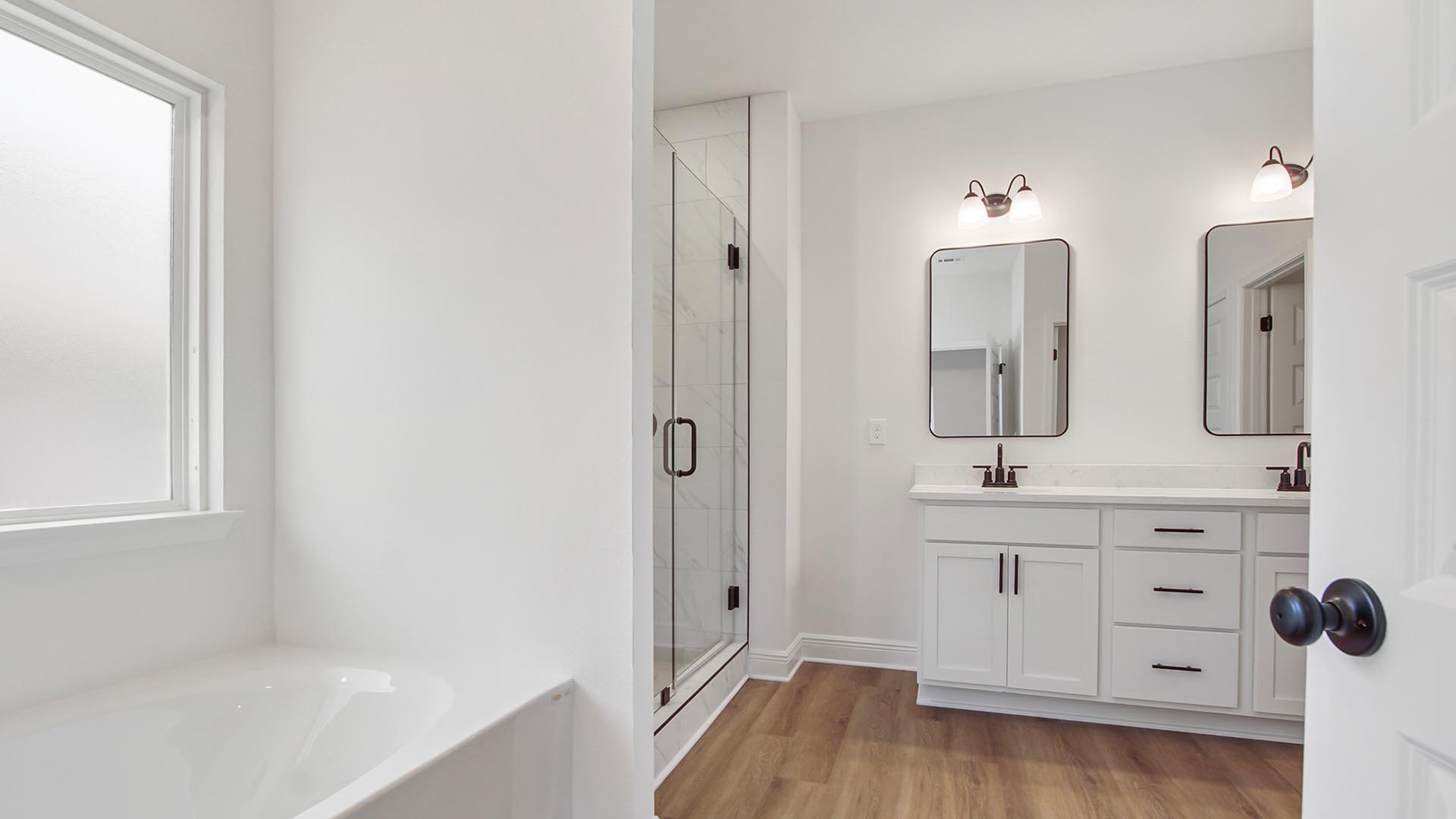 Primary bathroom has an elegant tile shower with glass enclosure and large soak tub