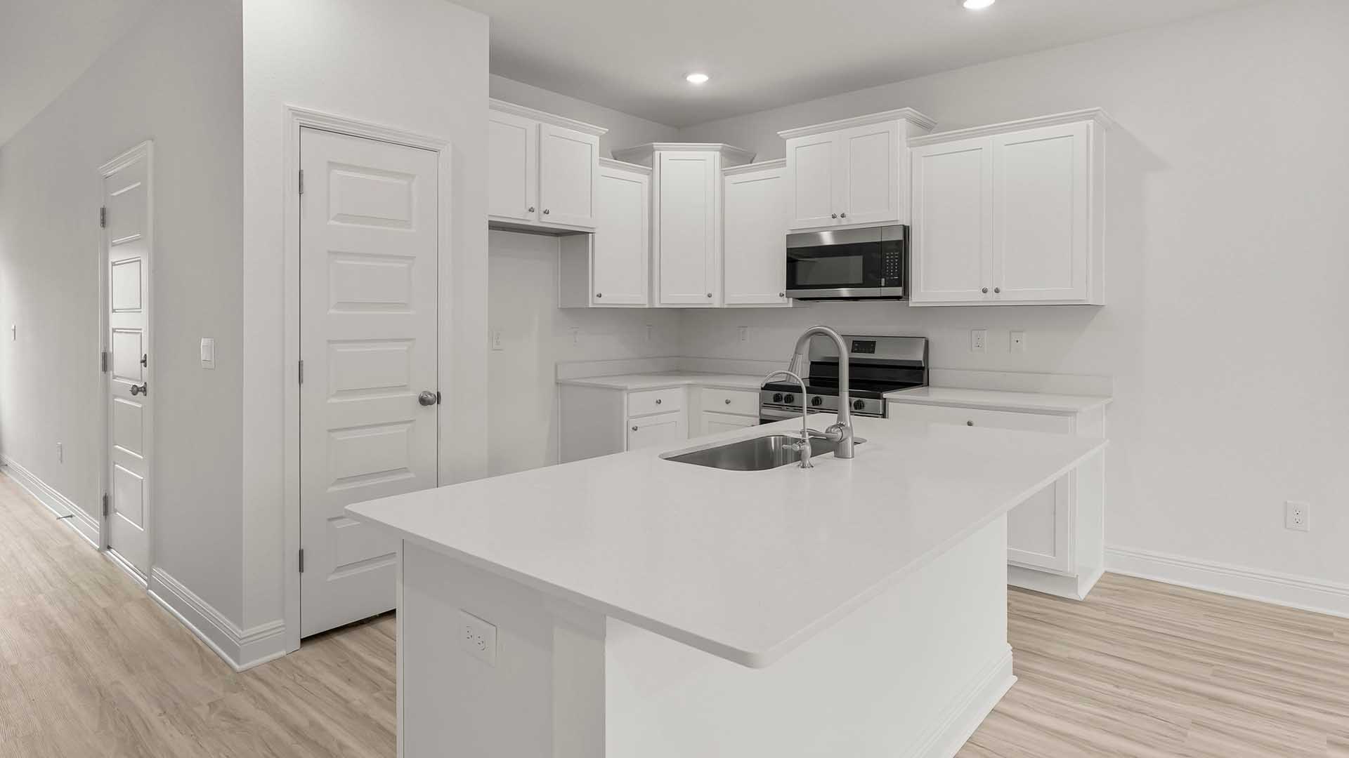 The kitchen is open with upper and lower cabinetry complemented by quartz countertops