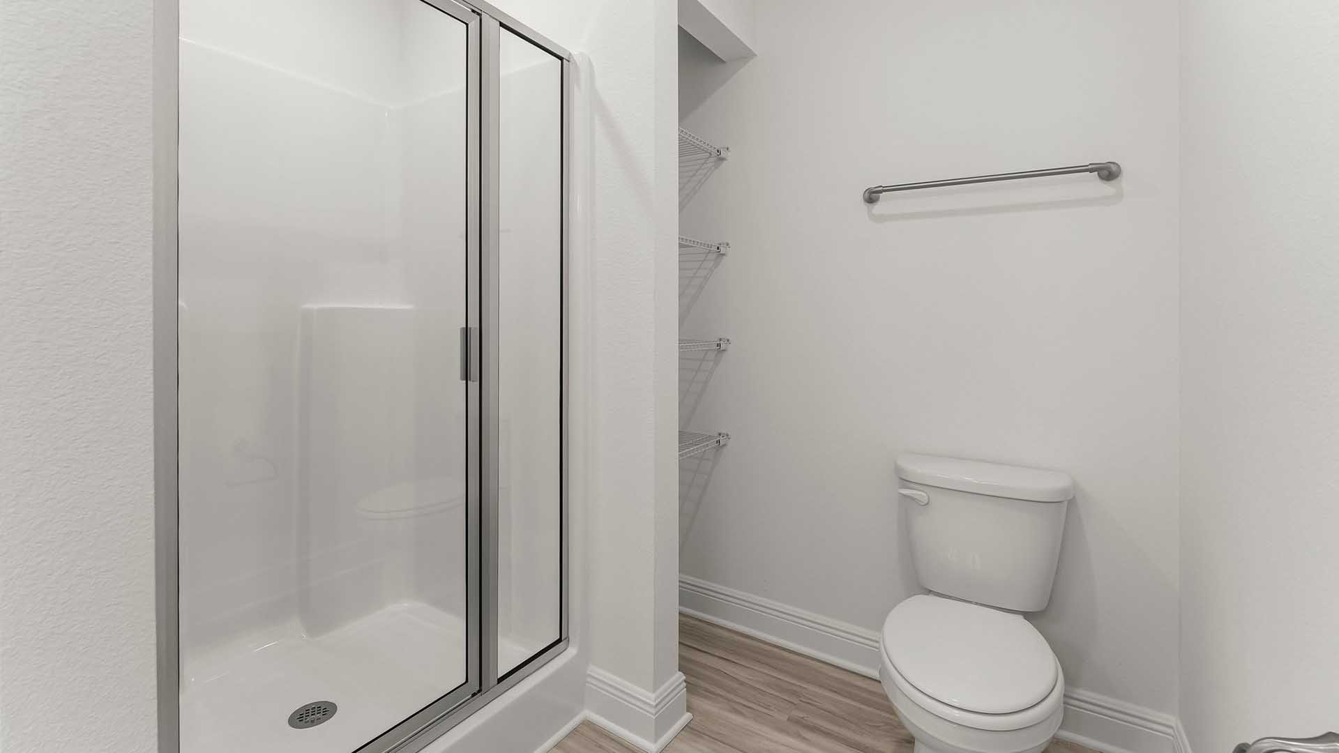 The primary bathroom has a shower with glass enclosure and a small linen storage area