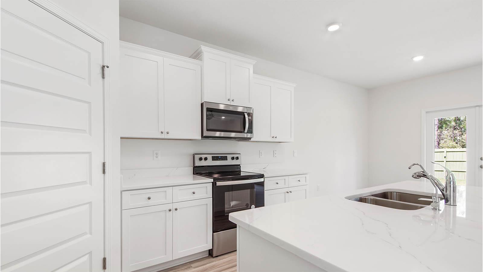 Kitchen with EVP flooring and walk in pantry and stainless-steel appliances next to dining area.
