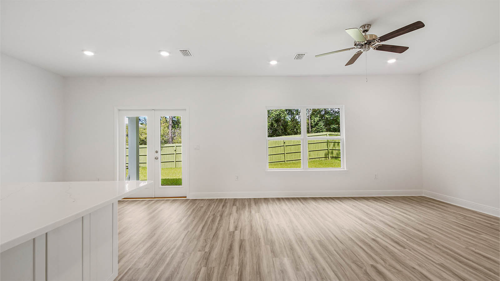 Open living area with EVP flooring and window and glass double doors to patio.