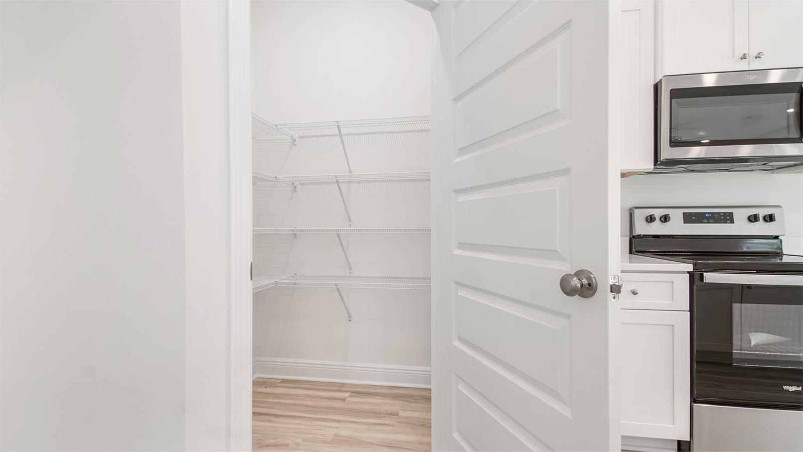 Walk in corner pantry in kitchen with EVP flooring and ventilated shelving.