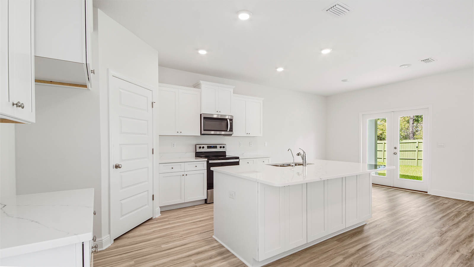 Large kitchen island with Quartz countertops and white cabinetry.