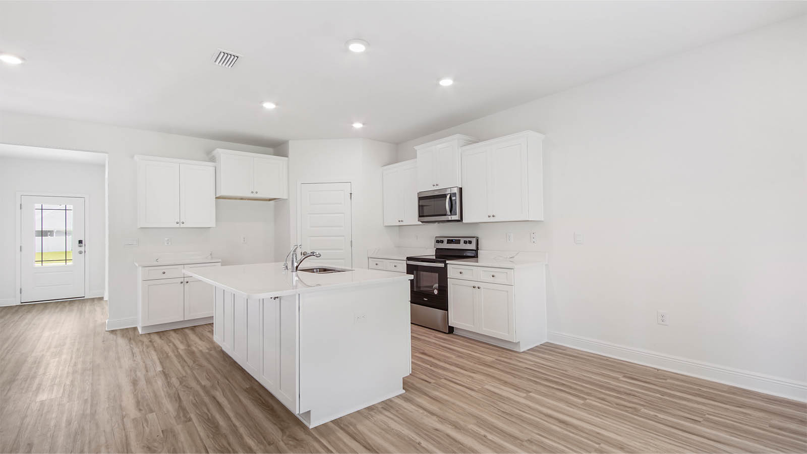 Kitchen with large island and EVP flooring and stainless-steel appliances.