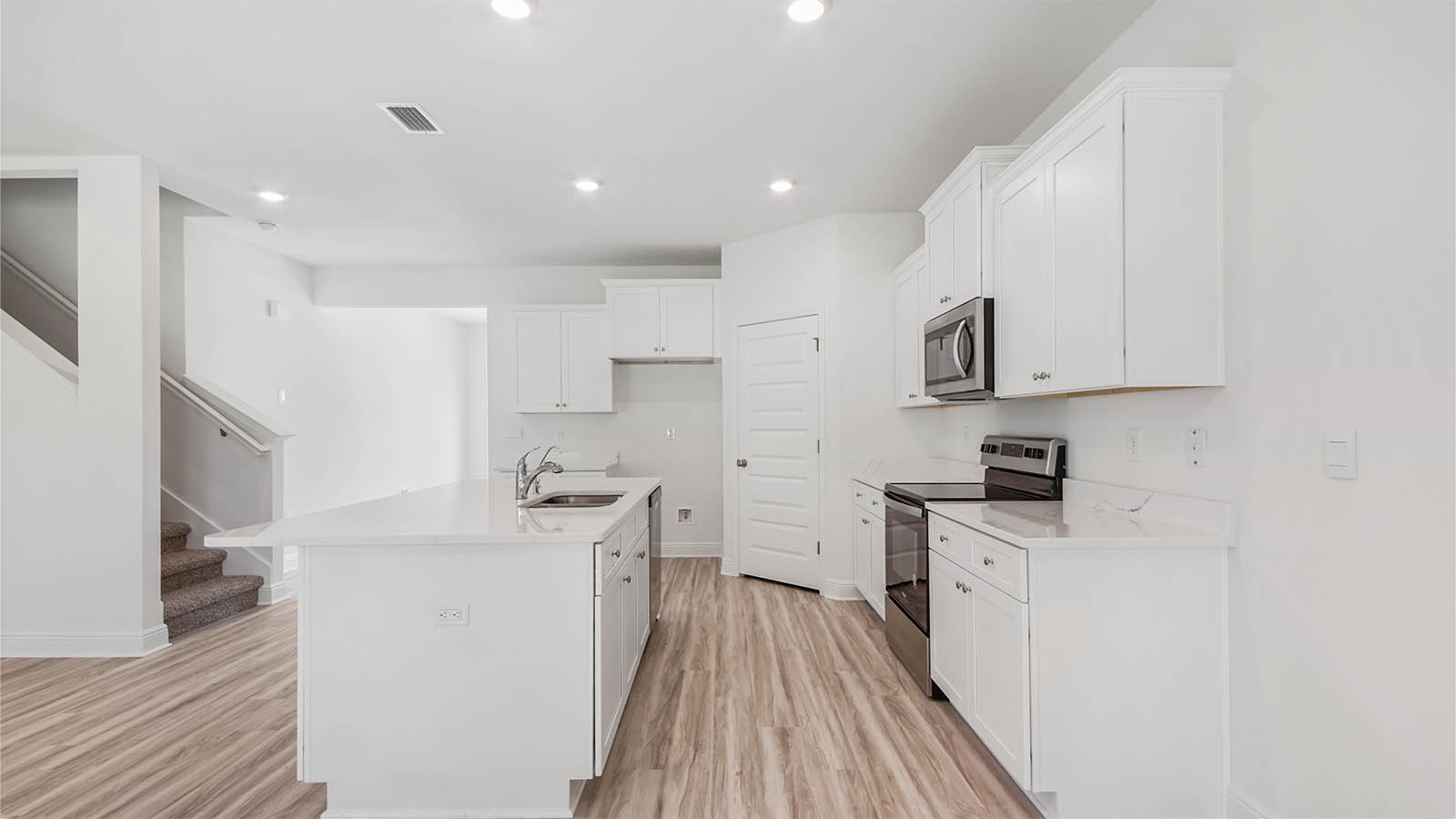 Kitchen with EVP flooring and quartz countertops and white cabinetry.