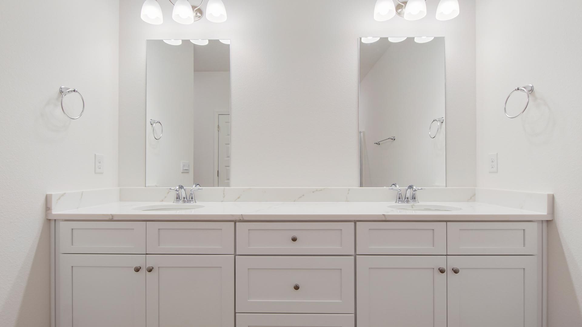 The vanity has quartz countertops and cabinetry with ivory color