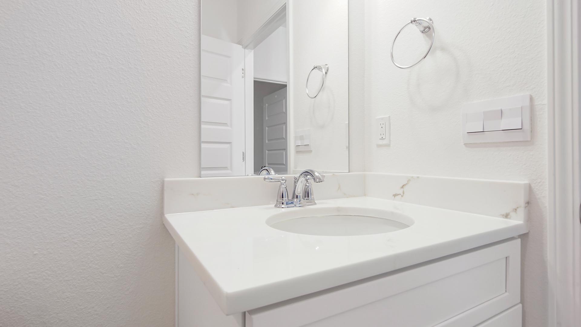 The guest bathroom has a single vanity with quartz countertops and lower cabinetry