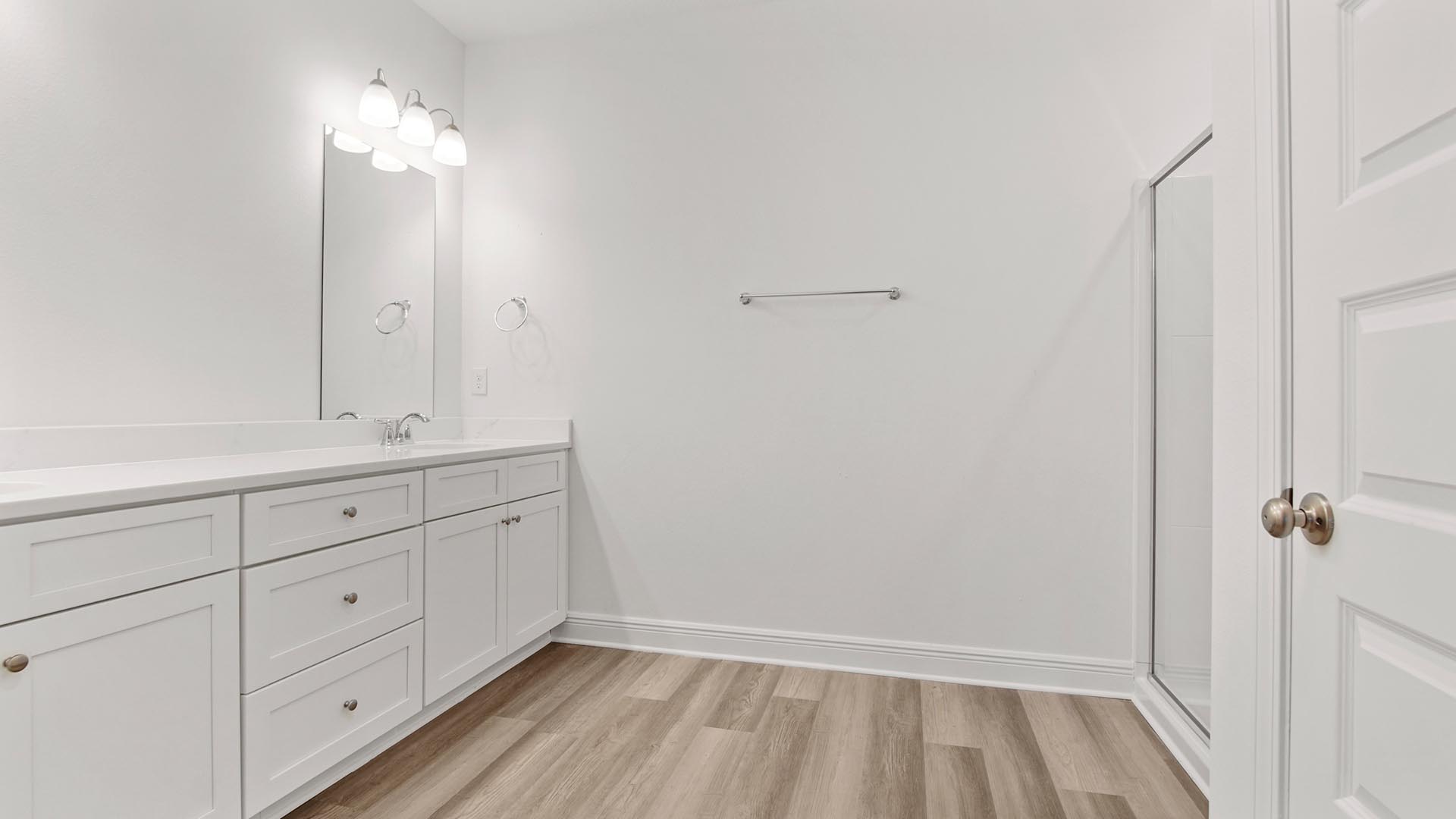 Primary bathroom with double vanity with white cabinetry and quartz countertops.
