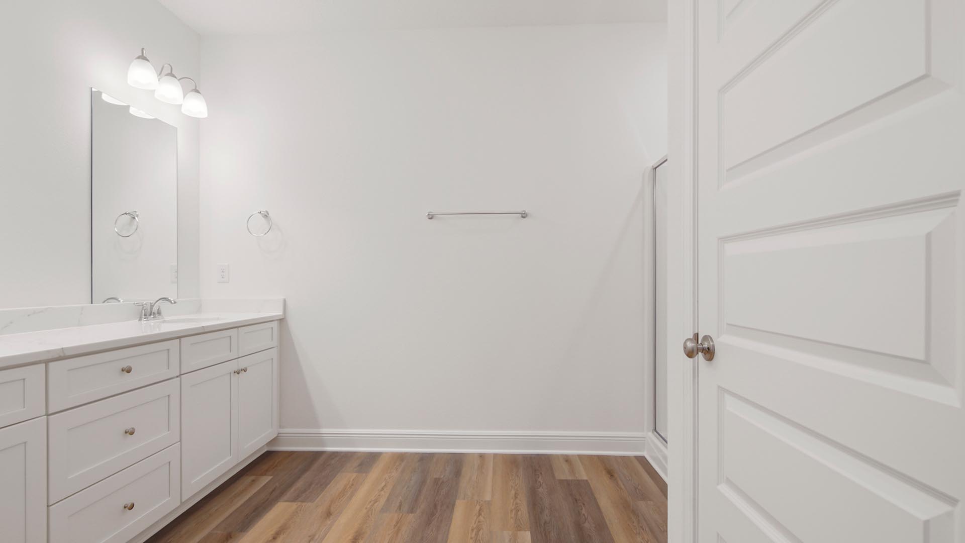 The primary bathroom has a vanity with lower cabinetry and quartz countertops