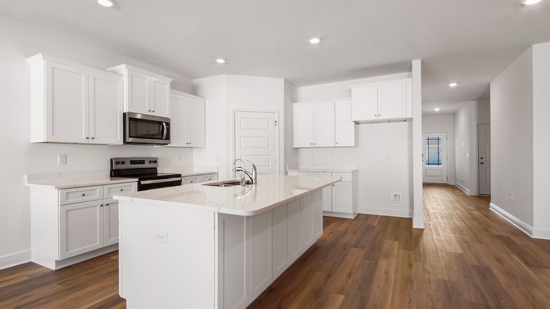 The kitchen has upper and lower cabinetry for storage. This image shows the island with the upper and lower cabinetry behind. The cabinetry is a ivory white