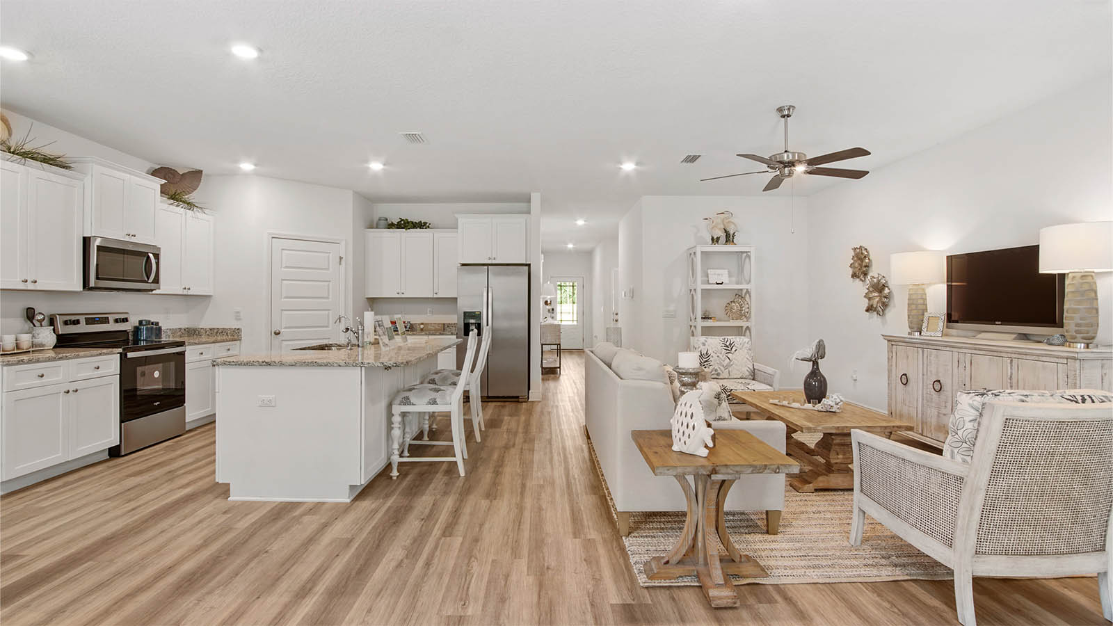 Kitchen island overlooking living area with EVP flooring and ceiling fan and hallway to foyer.