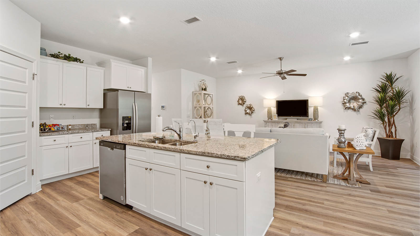 Kitchen island overlooking living area with white cabinetry and granite countertops.