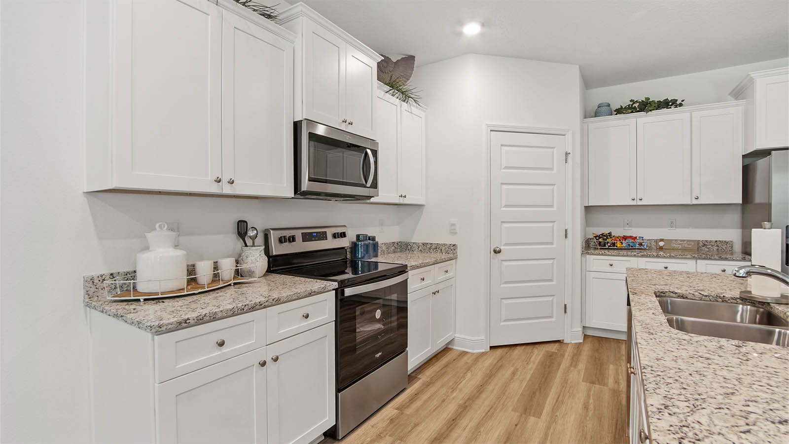 Kitchen with corner walk in pantry and stainless steel appliances and undermount sink in island.
