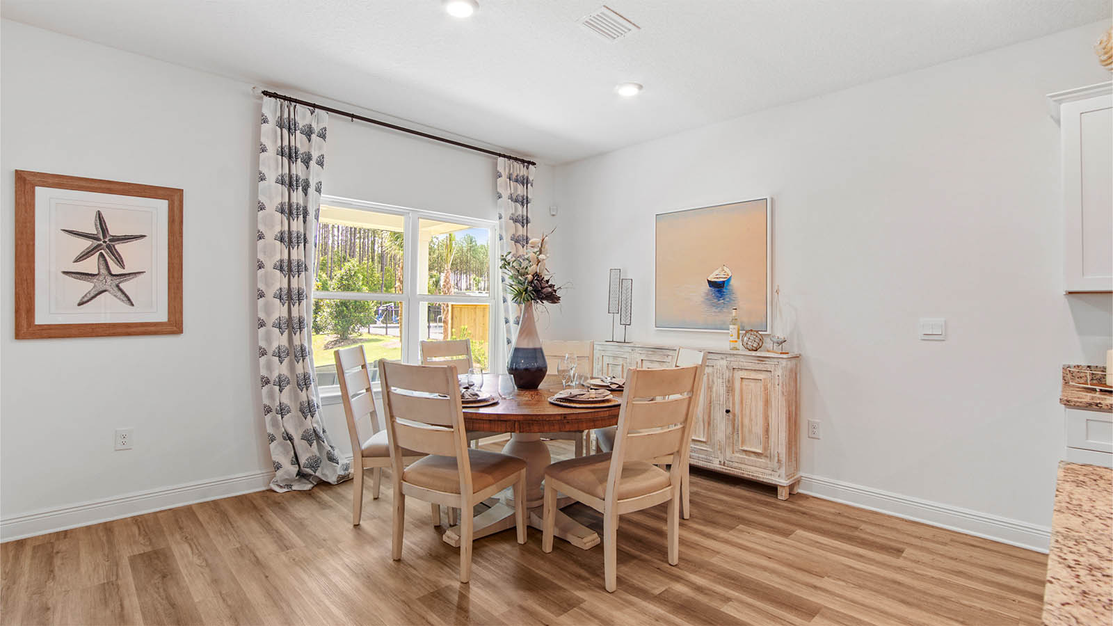 Dining area next to kitchen with EVP flooring and large window.