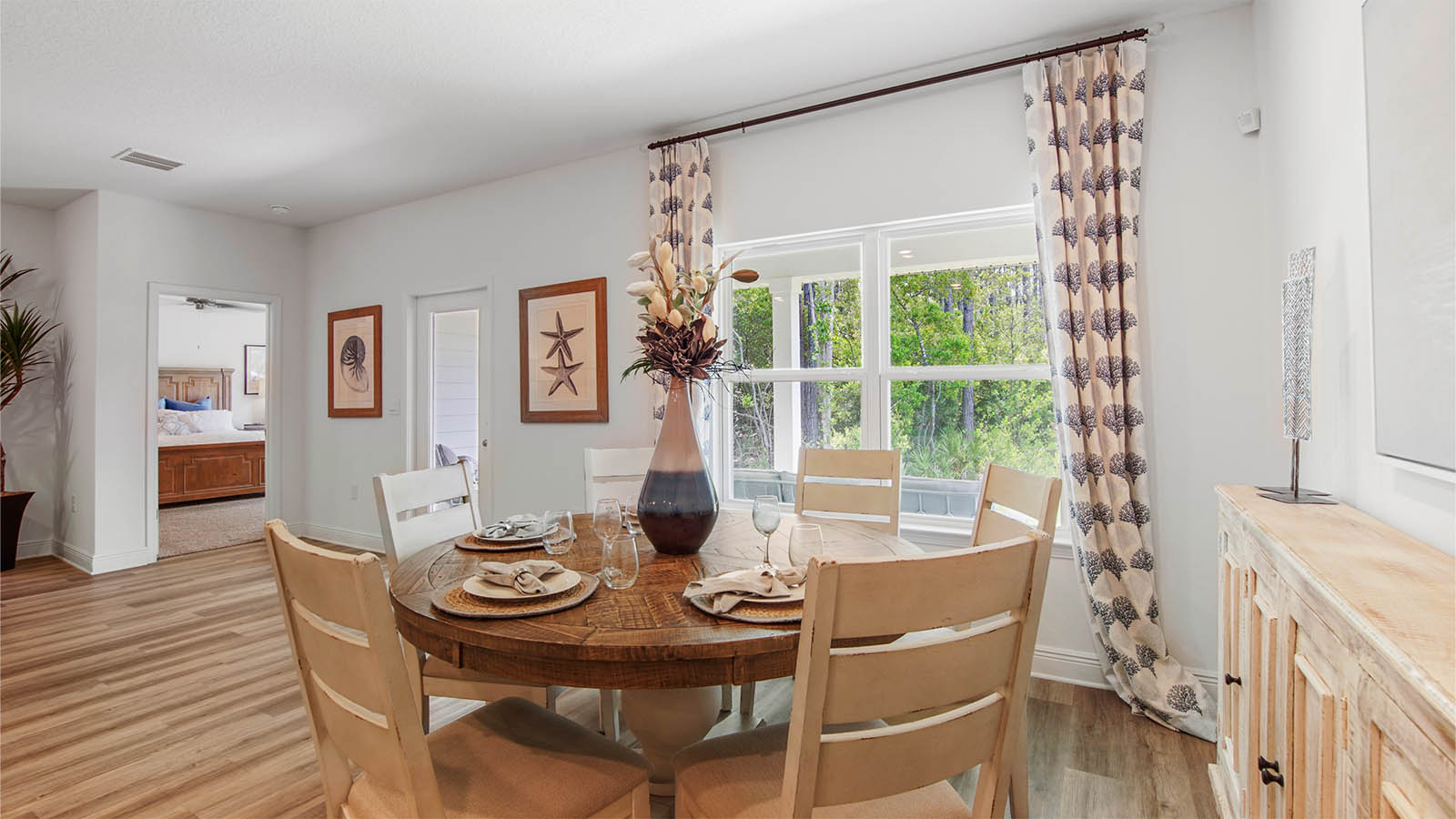 Dining area next to large window and glass back door and door to primary bedroom.