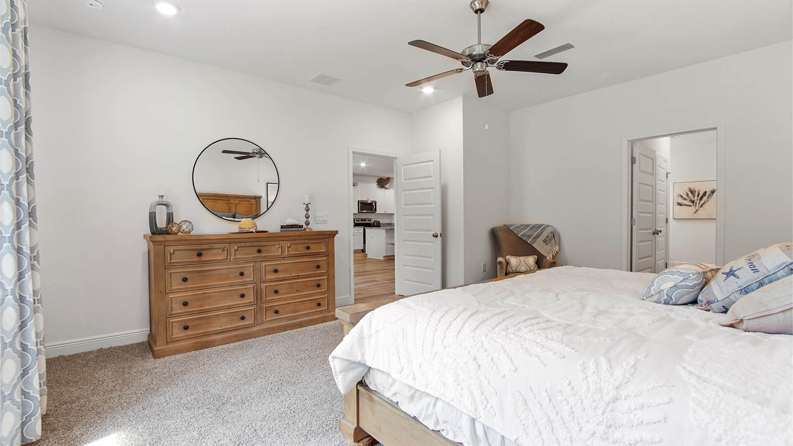 Primary bedroom with carpet flooring and ceiling fan and entrance to attached bathroom.