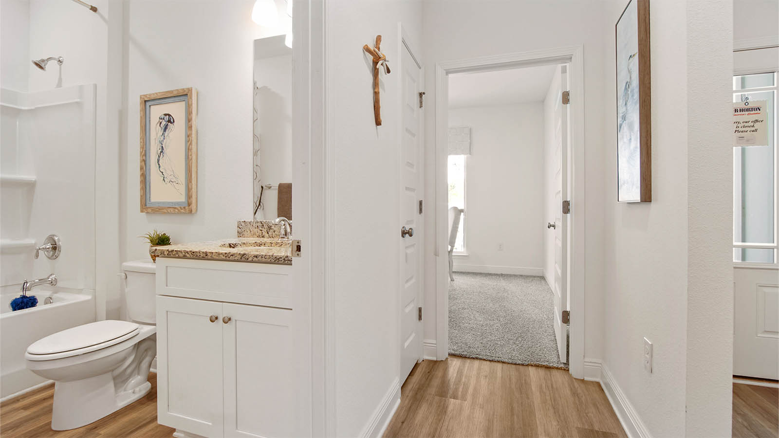 Hallway next to foyer leading to full guest bathroom and bedroom three and linen closet.