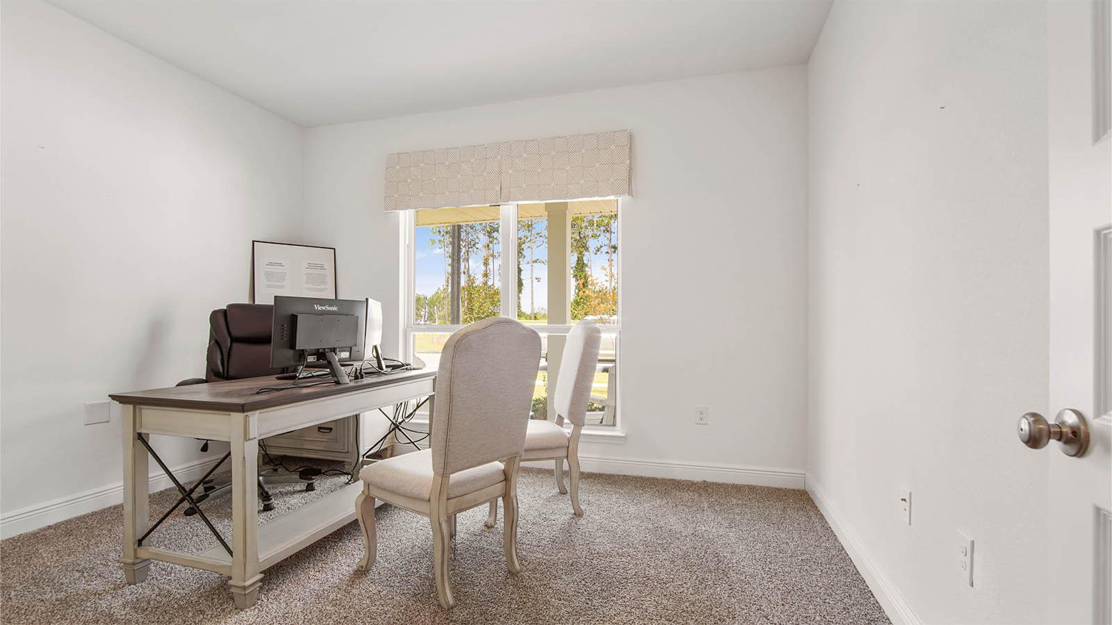 Bedroom four decorated as an office with a large window and carpet flooring.