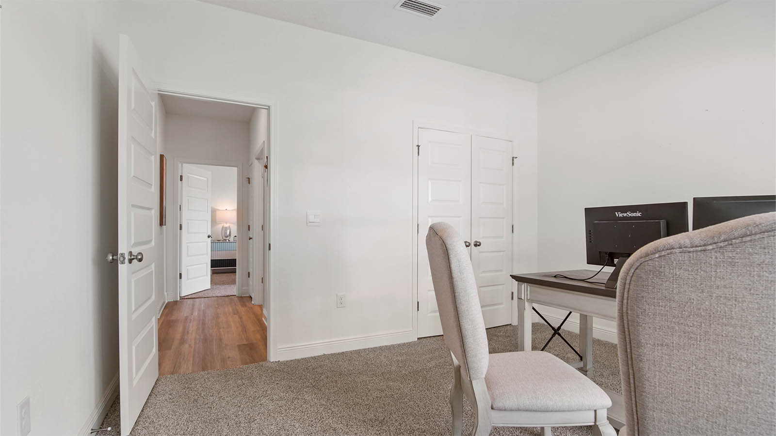 Bedroom four decorated as an office with a double door closet and carpet flooring.