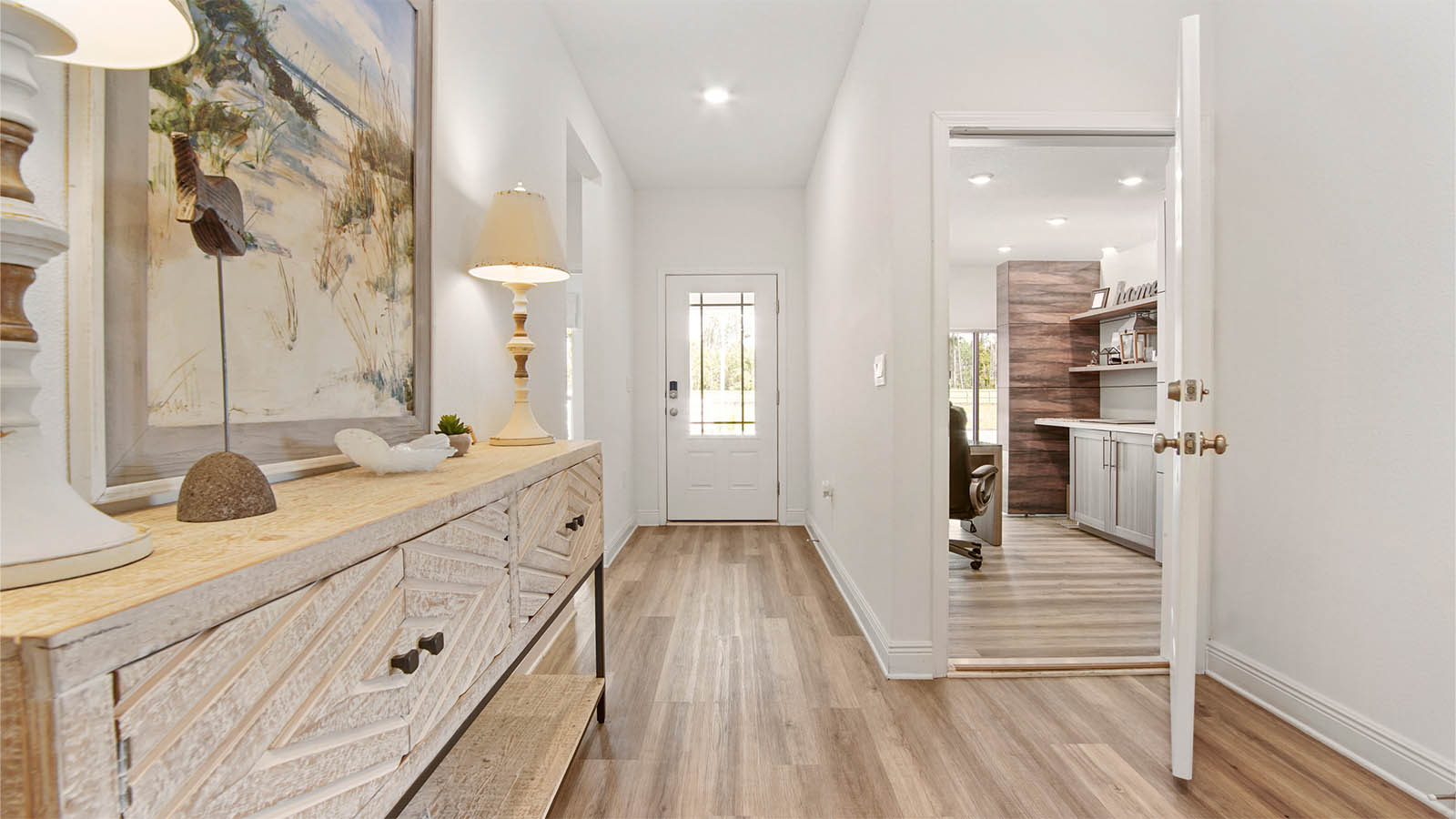 Foyer with glass front door and hallway to guest bedrooms and door to garage.