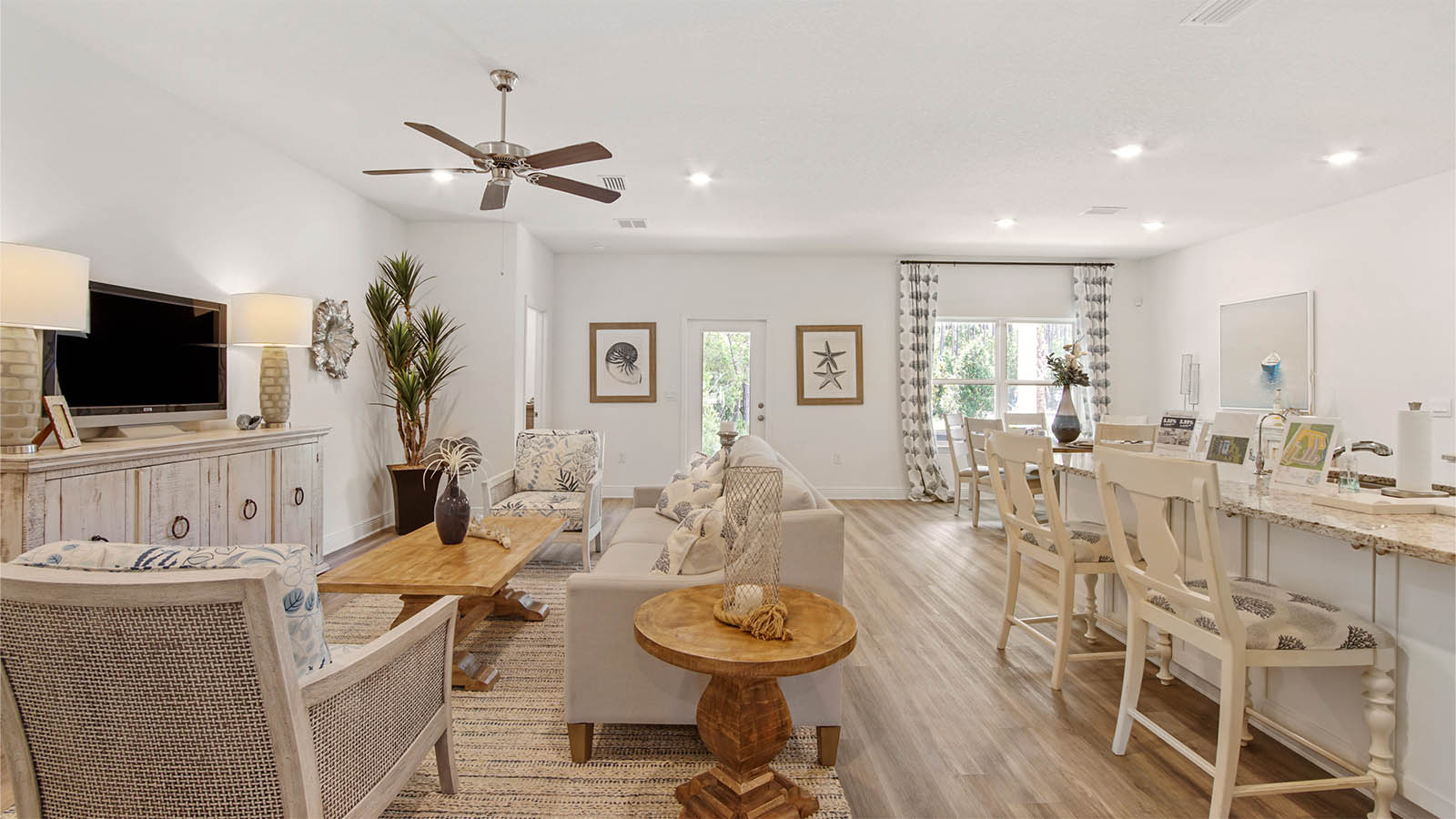 Open concept living area with large kitchen island and dining area and large window and glass back door to covered patio.