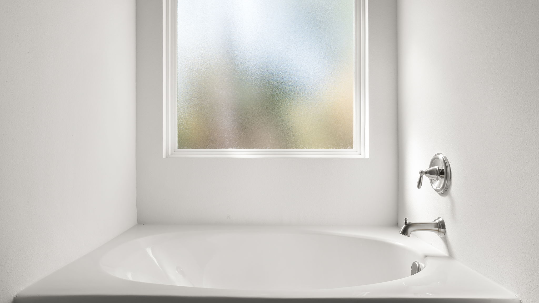 The soak tub has frosted glass window above