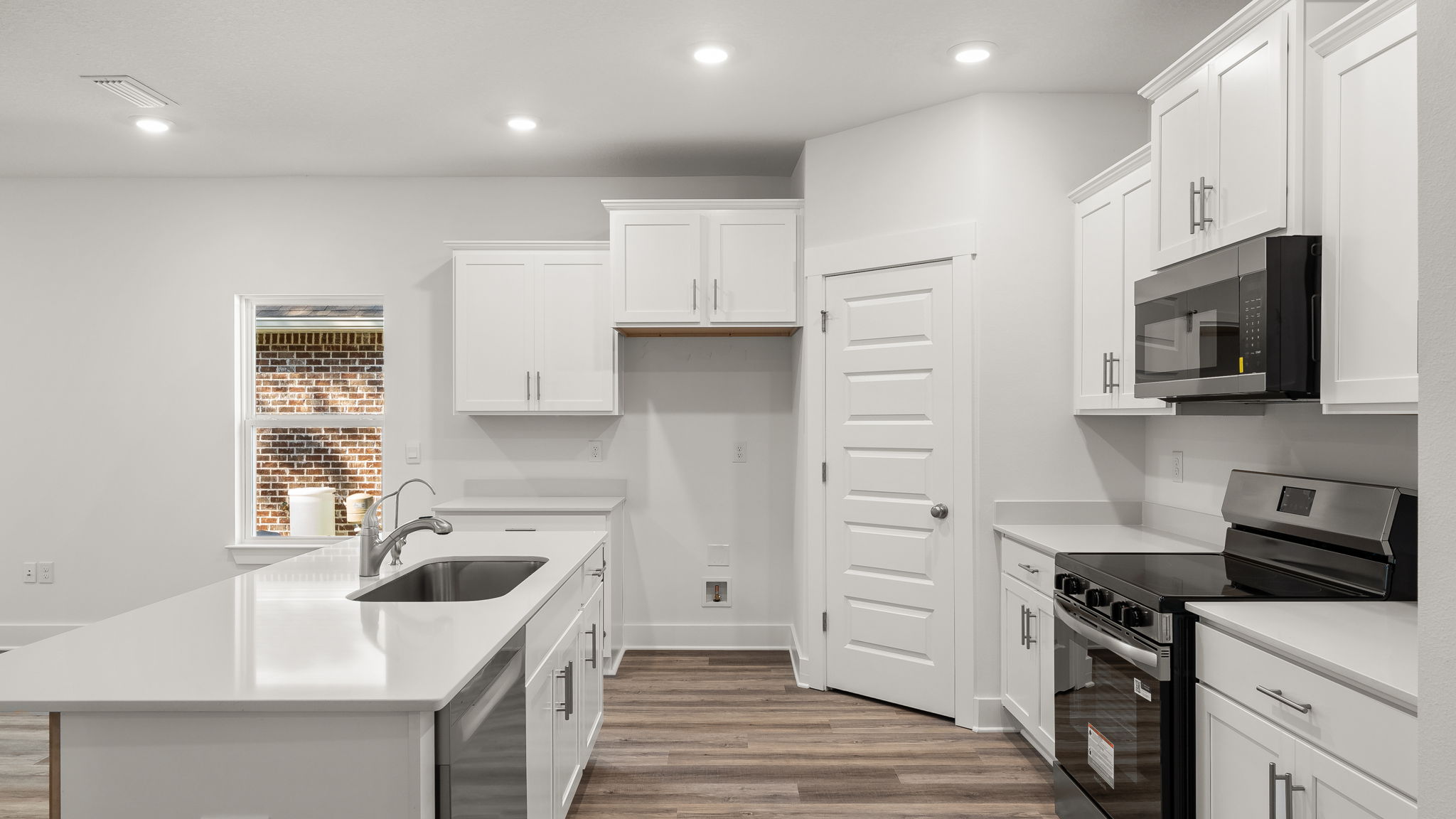 The kitchen has sleek quartz countertops and white cabinetry to complement