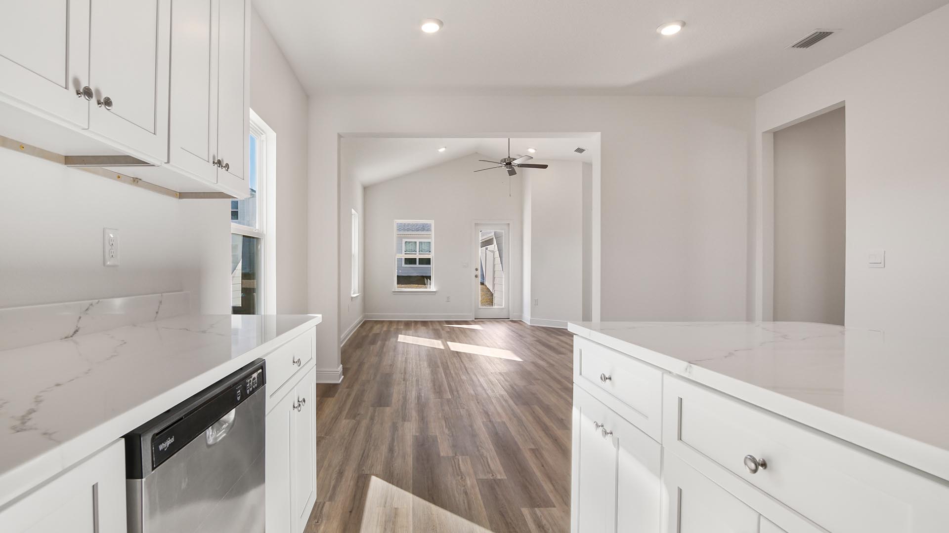 Kitchen with white cabinetry and quartz countertops and stainless steel appliances.